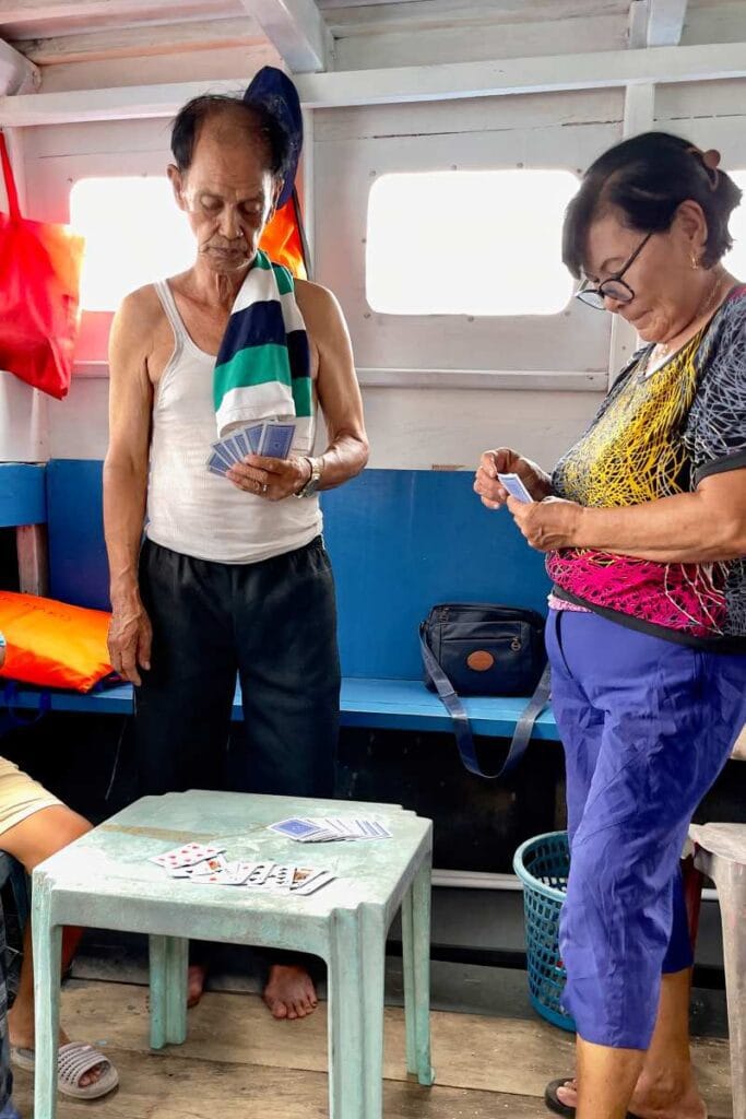 Passengers playing card games on a Bunaken ferry during the journey.