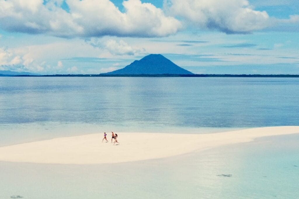 Group of friends on a sandbank near Nain Island with clear blue water