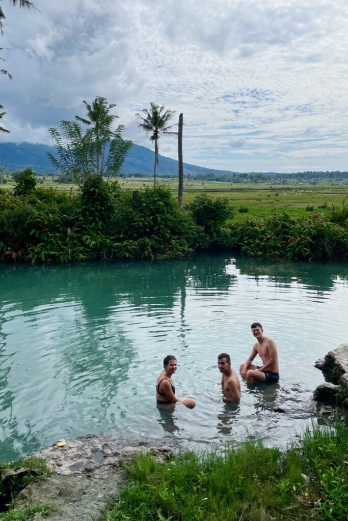 Three people in Ranolewo Hot Springs enjoying warm geothermal water